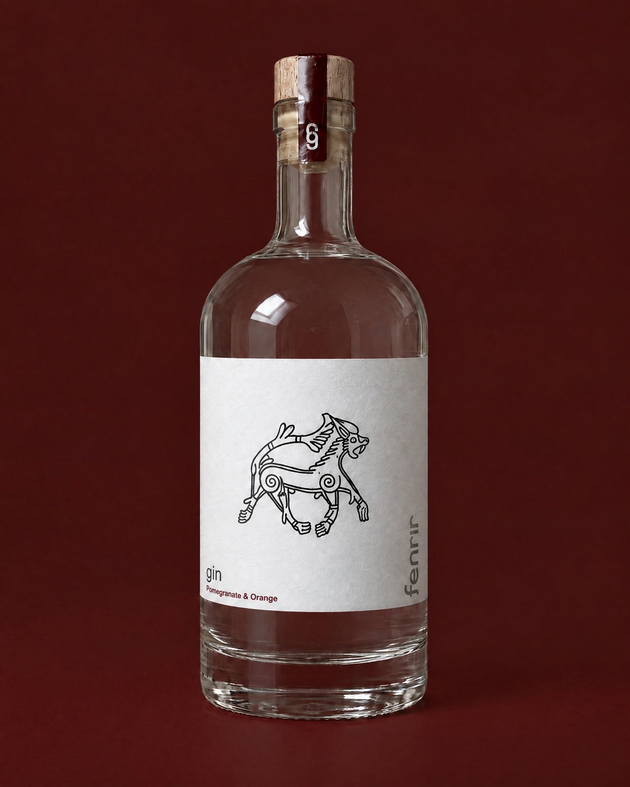 A bottle of Fenrir Pomegranate & Orange gin on a deep oxblood background