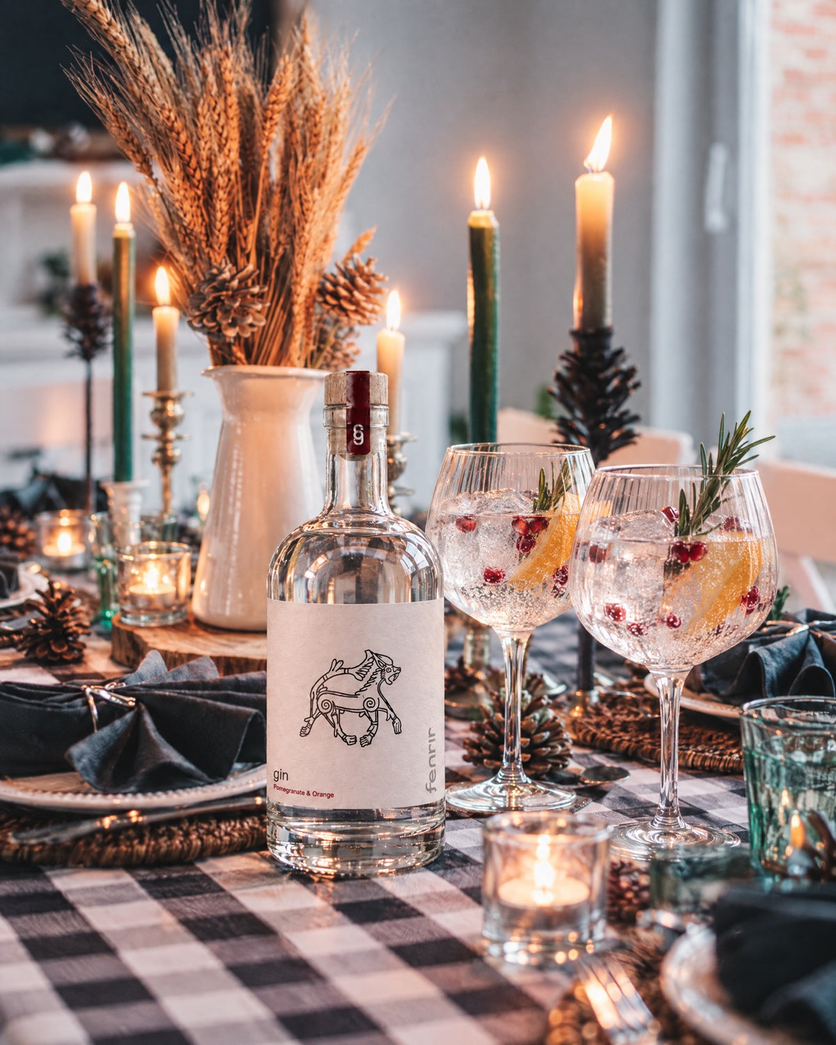 Fenrir gin and two gin and tonics with rosemary on a candlelit dinner table with wheat and pine cones